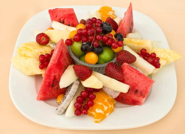 Fruits on a plate. Green plum, red currant, blueberry, strawberry, physalis, pitahaya