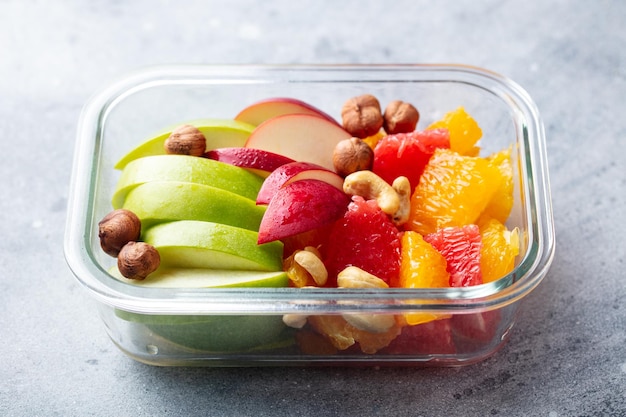 Fruits salad and nuts in a glass container Healthy eating Grey background Close up