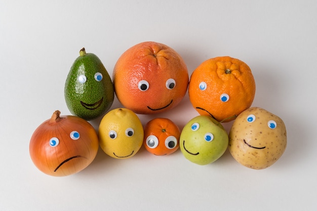 Photo fruits and vegetables with googly eyes and painted smiles. multinational company concept.