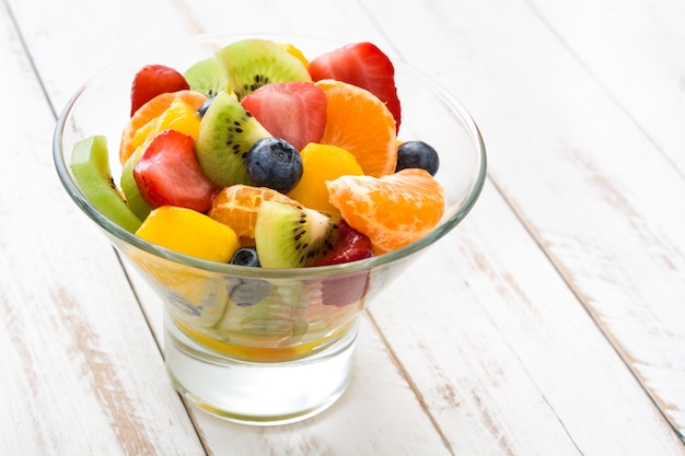 Fruitsalade in kristallen kom op witte houten tafel