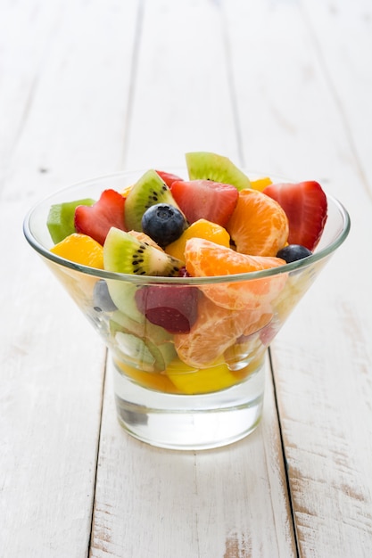 Foto fruitsalade in kristallen kom op witte houten tafel