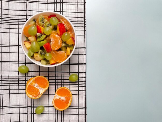 Foto fruitsalade met mandarijnen en druiven met een geruite handdoek op een lichte achtergrond bovenaanzicht