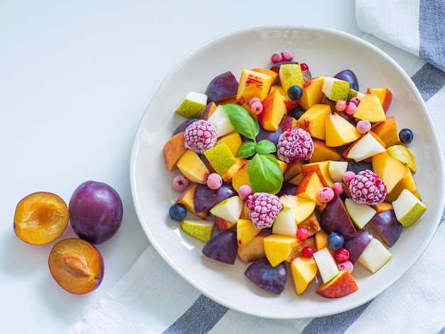 Fruitsalade met verse pruim perzik nectarine peer en bevroren frambozen