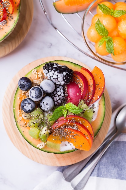 Foto fruitsalade met yoghurt in gesneden meloen meloen kom op tafel