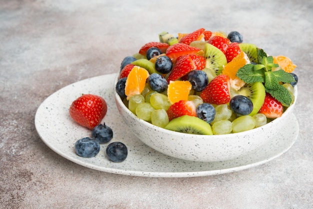 Foto fruitsalade van bosbessen, aardbeien, druiven en kiwi in een bord, een kopie van de ruimte