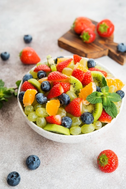 Fruitsalade van bosbessen, aardbeien, druiven en kiwi in een bord, selectieve focus