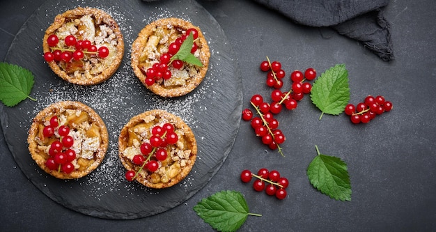 Fruittaart met rode aalbessen bestrooid met poedersuiker op een zwarte tafel heerlijk dessert