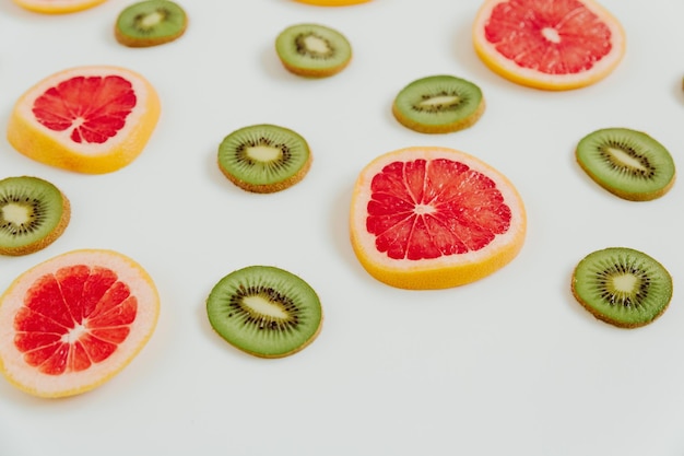 Fruity pattern of kiwi and grapefruit slices on the white background Minimal colourful trend style