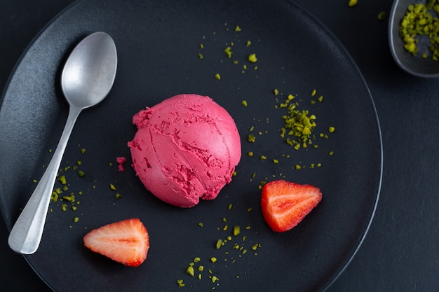 Fruity strawberry Ice cream scoop served on plate with fruits and pistacchios. Top View.