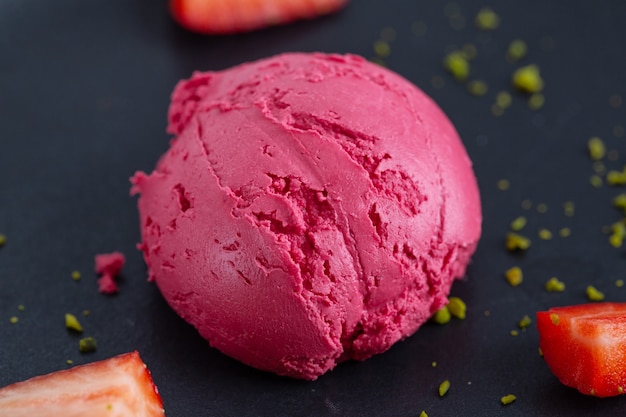 Fruity strawberry Ice cream scoop served on plate with fruits and pistacchios. Top View.