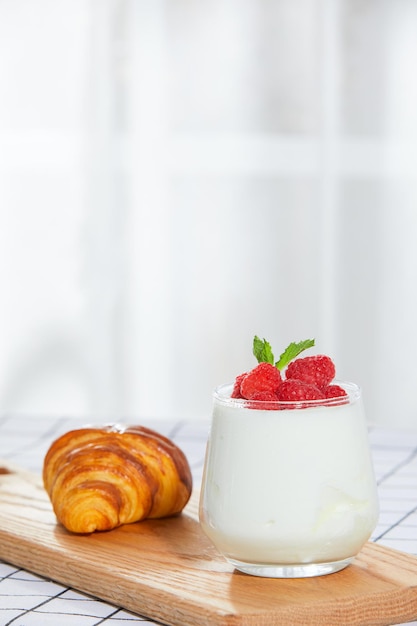 Fruityoghurt en croissants op tafel voor het raam