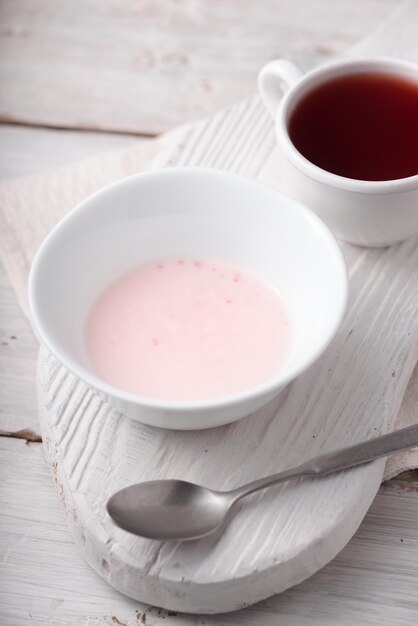 Fruityoghurt en kopje thee op de witte houten tafel