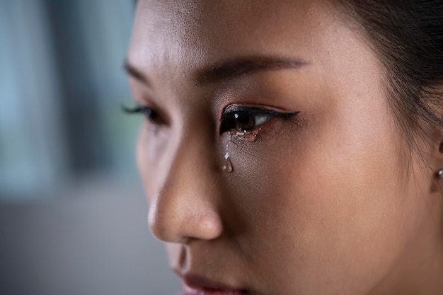 写真 欲求不満で落ち込んでいる若いアジア人女性が彼女の目から涙を流して泣いている悲しいアジア人女性が問題について考えて落ち込んでいる