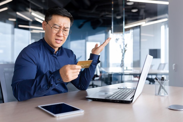 Frustrated asian man trying to make banking transaction and purchase in online store businessman