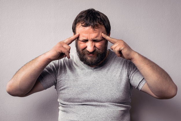 欲求不満のあごひげを生やした男が手で頭に触れ、目を閉じたまま