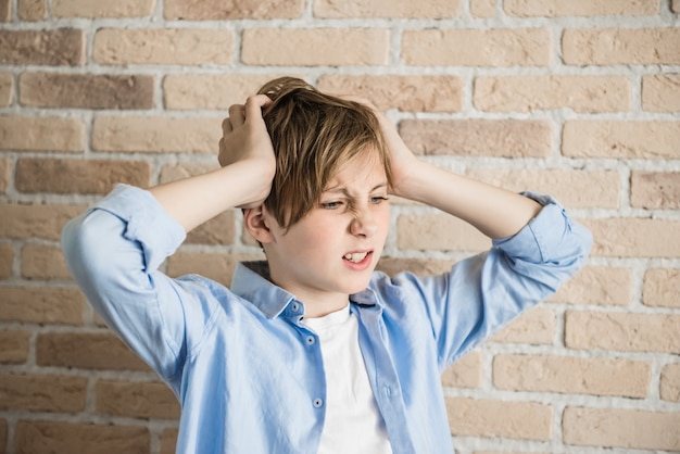 Foto il ragazzo frustrato si sta strappando i capelli. frustrazione, depressione, concetto di problemi genitoriali