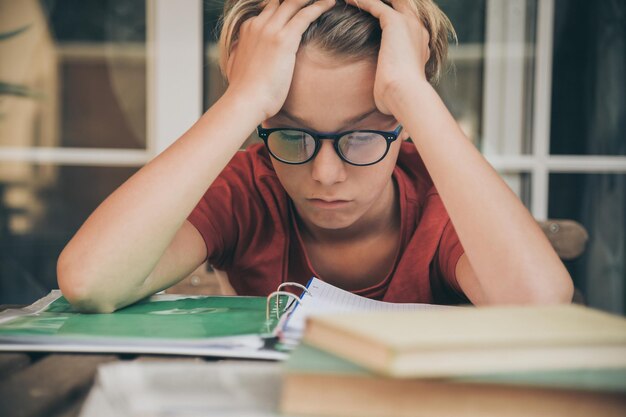 Photo frustrated boy with head in hands studying