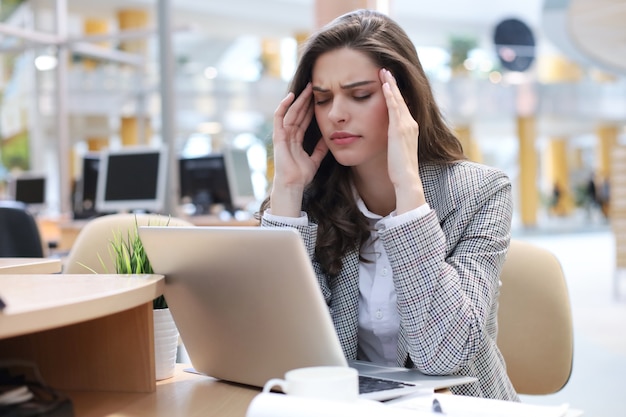 Frustrated business woman looking exhausted while sitting at her working place.