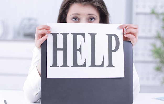 Frustrated business woman showing a sheet with the word help . photo with copy space.