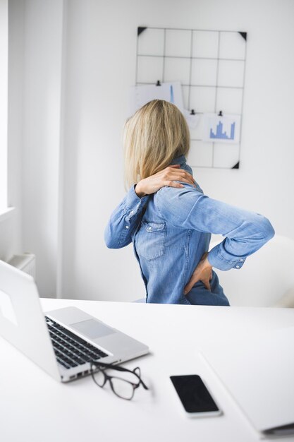 Foto una donna d'affari frustrata che ha mal di schiena mentre lavora da casa