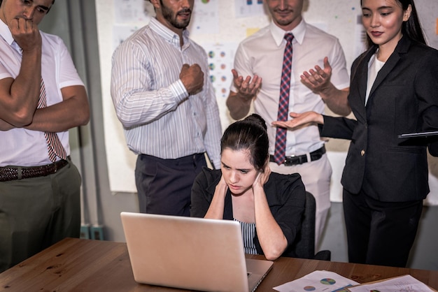 Frustrated businesswoman using laptop while explaining colleagues in meeting at board room