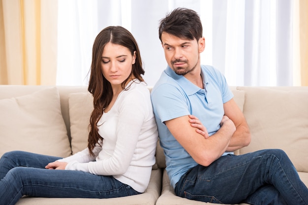 Frustrated couple are sitting on couch.