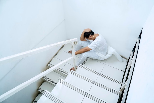 Frustrated doctor in protective suit sits on stairs