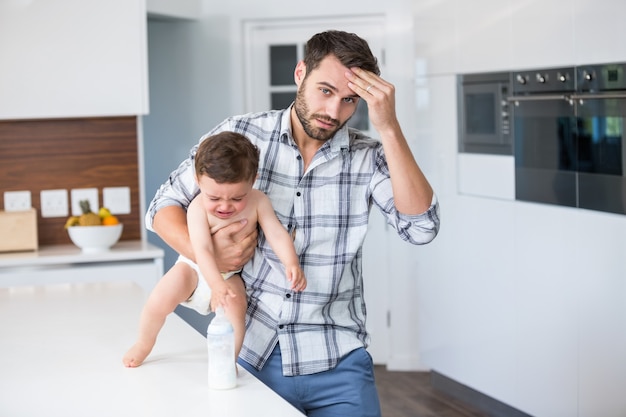 Frustrated father holding crying baby boy