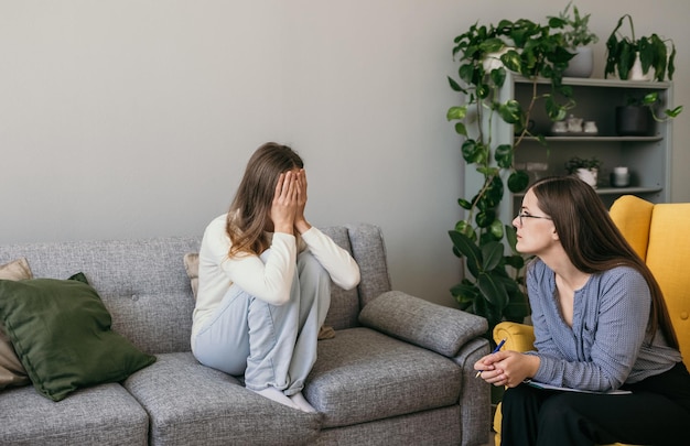 a frustrated female patient is sitting on the couch in the psychologist's office. The psychologist doctor conducts the reception of a mentally ill patient in the office