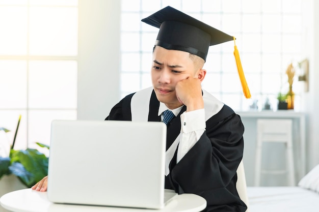 Разочарованный выпускной мужчина пытается учиться онлайн дома
