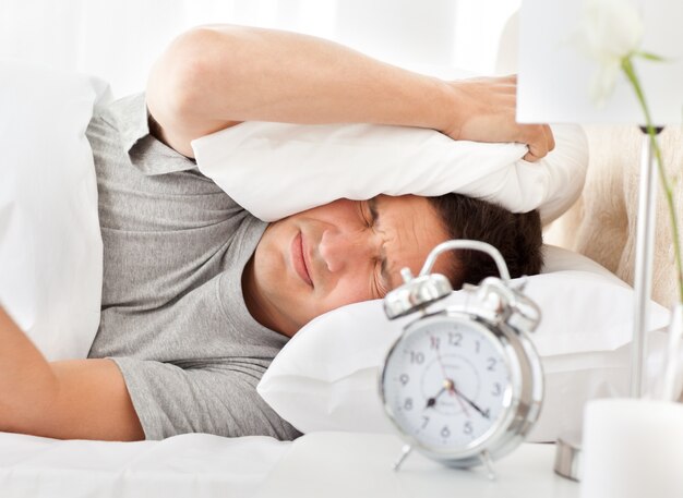 Frustrated man listening to his alarm clock