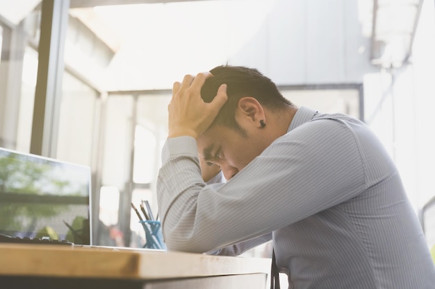 frustrated man sitting by paper and laptop on table