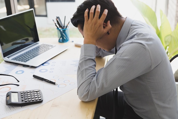 テーブルに紙とラップトップで座っている挫折した男