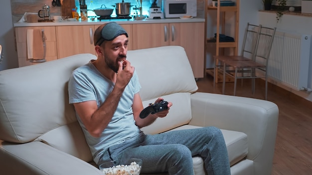 Frustrated man with sleep mask losing videogame competition