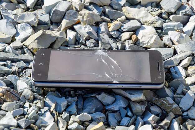 Frustrated phone on the rocks Glass shattered on rocks on a sma