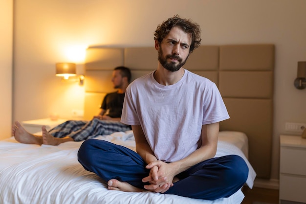 Ragazzo triste frustrato sedersi sul letto pensare a problemi di relazione coppia gay premurosa dopo litigio perso nei pensieri amanti sconvolti considerare rompere persona offesa delusa dal fidanzato