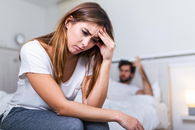 Frustrated sad girlfriend sit on bed think of relationship problems, thoughtful couple after quarrel lost in thoughts, upset lovers consider break up, offended person disappointed by boyfriend