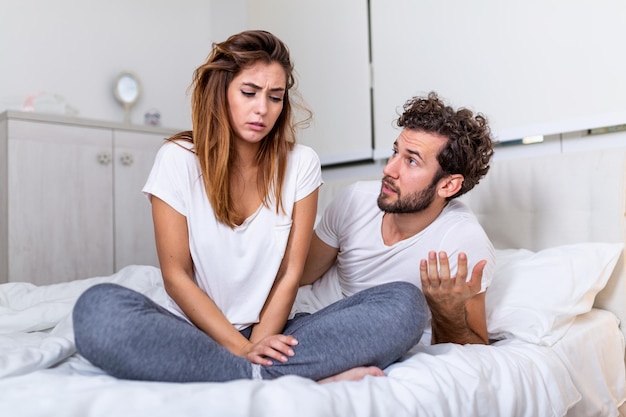 Frustrated sad girlfriend sit on bed think of relationship problems, thoughtful couple after quarrel lost in thoughts, upset lovers consider break up, offended person disappointed by boyfriend