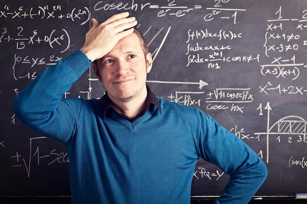 Photo frustrated teacher standing against blackboard in classroom
