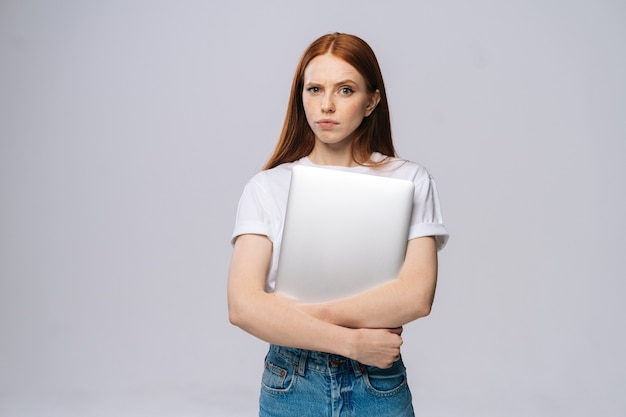 Frustrated upset young business woman or student holding laptop computer and looking at camera