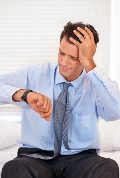 Foto orologio frustrato e uomo d'affari in ritardo a casa per errore di sonnolenza e burnout persona maschile stressata e mal di testa con paura del tempo per l'appuntamento in azienda aziendale e lavoro