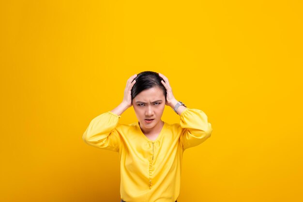 Frustrated woman against yellow background