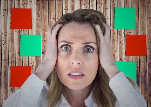 Frustrated woman with hands on her face against sticky note on wooden background