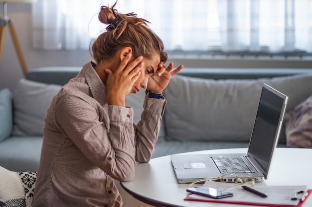 Frustrated woman working at office desk on laptop