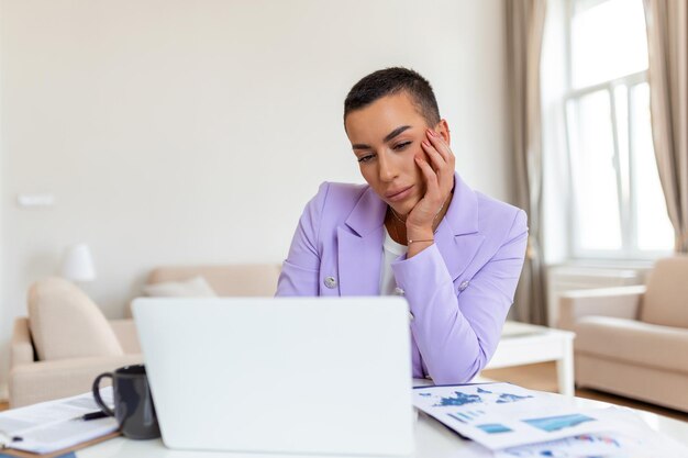 Frustrated young african american businesswoman working on a\
laptop sitting at desk in office