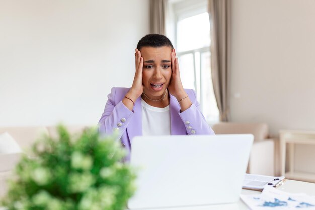 Frustrated young African American businesswoman working on a laptop sitting at desk in office