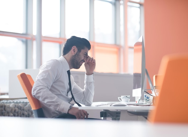 Giovane uomo d'affari frustrato che lavora al computer desktop all'interno dell'ufficio di avvio moderno