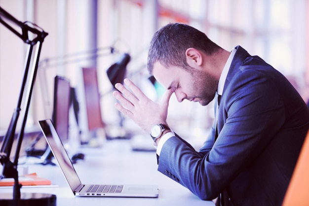 Frustrated young business man working on laptop computer at office