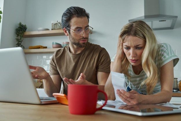 Frustrated young couple discussing home finances at the domestic kitchen