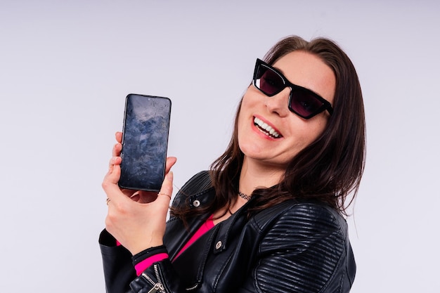 A frustrated young woman with a broken phone in her hands white isolated background broken gadget